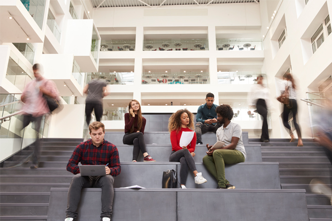 The photo shows several young people on a staircase. Some are going up and down the stairs, others are sitting on the steps.